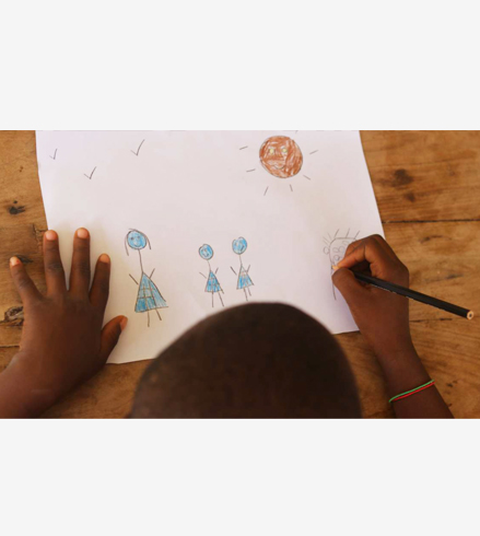 Vue de haut d'un enfant dessinant une famille